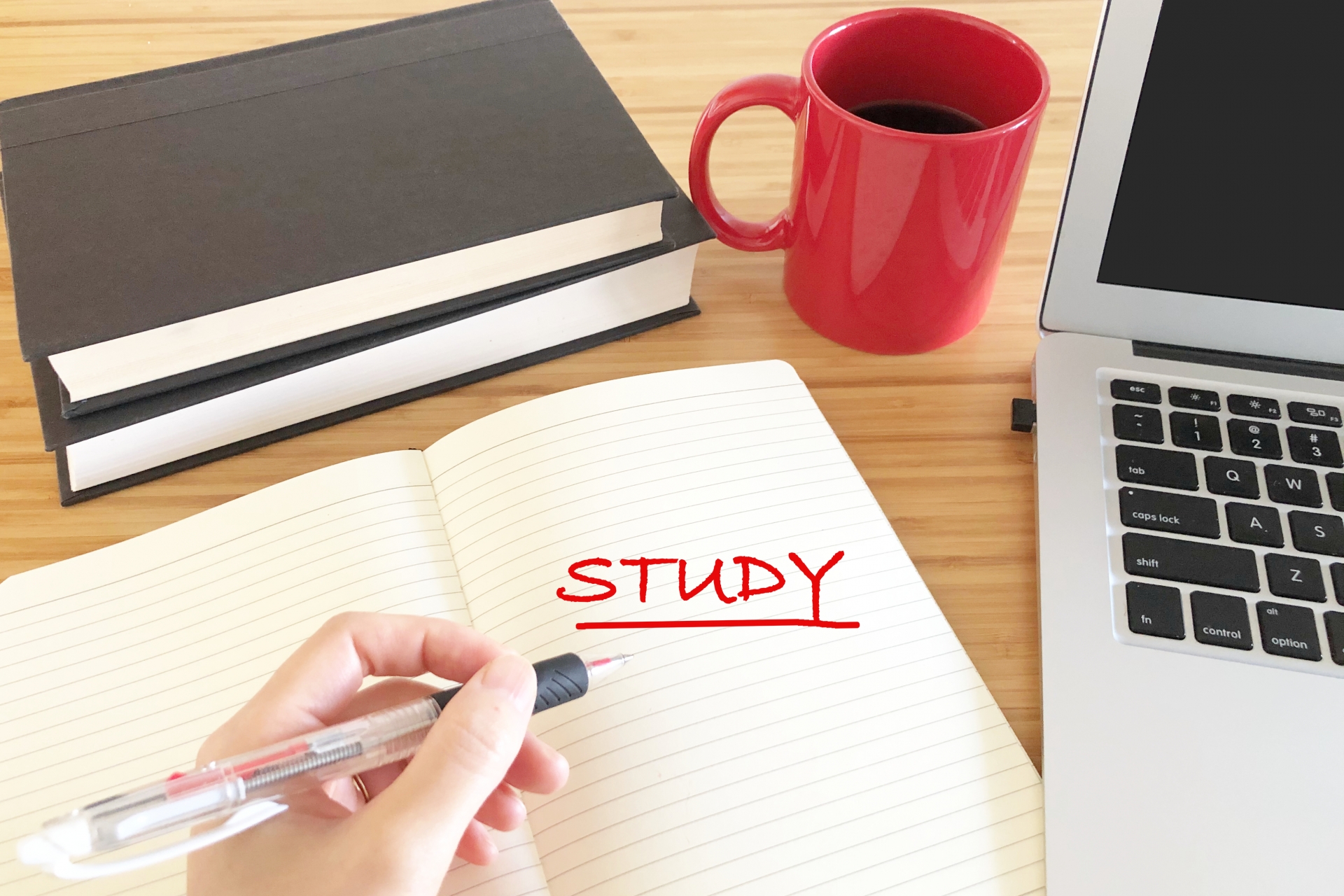 STUDYと赤ペンで書いている。パソコンとコーヒー